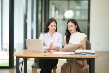 Businessman, two Asian women give advice, discuss work, documents on laptop at office	
