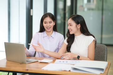 Businessman, two Asian women give advice, discuss work, documents on laptop at office