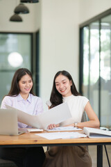 Businessman, two Asian women give advice, discuss work, documents on laptop at office