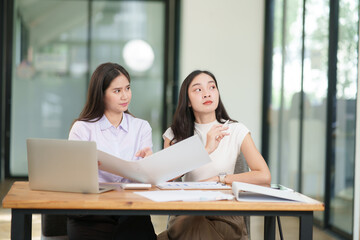 Businessman, two Asian women give advice, discuss work, documents on laptop at office