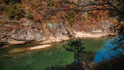 Autumn scenery of the Hantan River Columnar Joint Road, with canyons and cliffs formed by the river flowing through the volcanic terrain. (emerald water and colorful leaves)