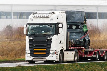 Tow truck carrying two wrecked car on trailer