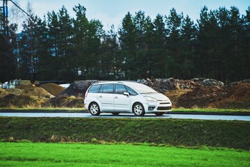 SUV on rainy countryside drive with green and dirt hills