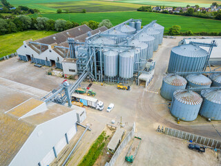 Interesting view of a grain storage and drying facility showing vehicles being loaded with dry...