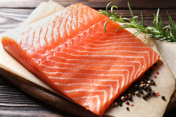 Piece of fresh salmon and spices on wooden table, closeup