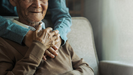 Happy granddaughter hugs old grandpa at home and encourages grandpa. Elderly care concept. Happy...