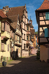 Typical architecture in Alsace in northeastern France. Charming cityscape view of narrow medieval cobblestone street between colorful stone houses in Kaysersberg, France