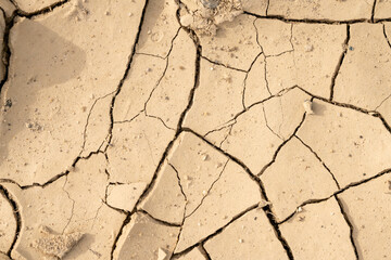 Close up of cracked brown dry soil. Pattern of cracks and chipped off pieces of dirt. Concept of erosion, climate change, environment.