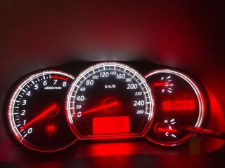 A close up photo of a car dashboard at night, illuminated with a red glow.