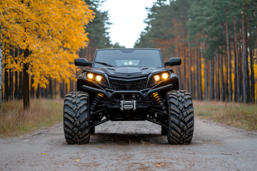 Fototapeta premium All terrain vehicle in forest setting, showcasing its rugged design and powerful stance. vibrant autumn foliage adds striking contrast to black vehicle
