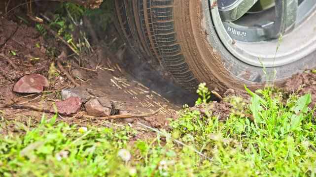 car tire slipping while stuck in a dirt, heating up and steaming in attempt to get free, closeup with selective focus
