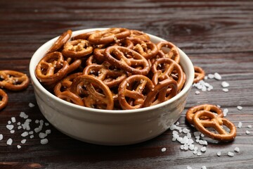 Tasty pretzel crackers with salt on wooden table, closeup