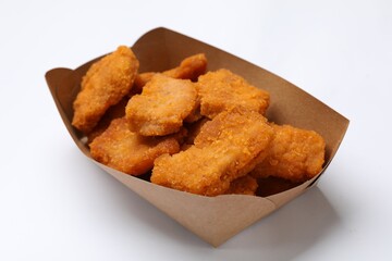 Delicious chicken nuggets in carton box on white background