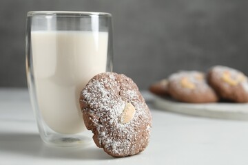 Tasty chocolate cookie with cashew and glass of milk on white table, closeup. Space for text