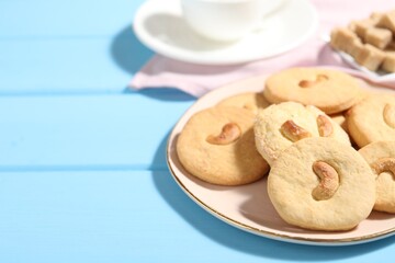 Plate with tasty cashew cookies on light blue wooden table, closeup. Space for text