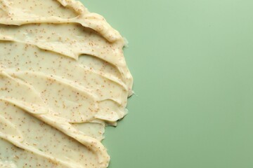Smears of body scrub on light green background, top view. Space for text