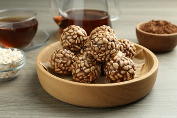 Tasty chocolate puffed rice balls served with tea on wooden table, closeup