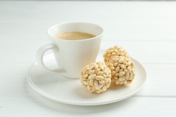 Tasty puffed rice balls and coffee on white wooden table, closeup