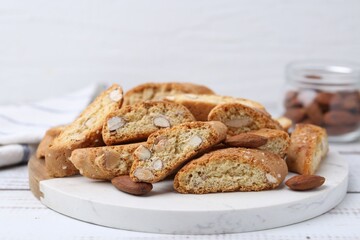 Tasty almond biscuits (Cantuccini) and nuts on white wooden table, closeup