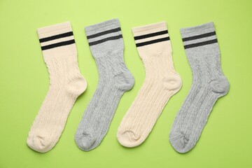 Different comfortable socks on light green background, flat lay