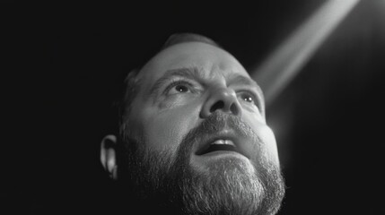 Dramatic close-up portrait of a man with a beard looking upwards