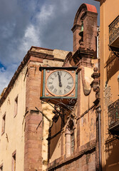 An old historic wall clock on the facade of a church in the old town centre of Bosa, Sardinia