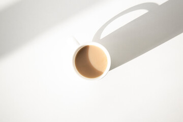 White cup with coffee on a white table. Top view, flat lay