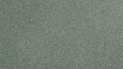 Fototapeta premium gray textured smooth surface view at right angles, grainy dotted relief texture of green-gray shade with empty copy space, fragment of sports flooring made of rubber crumb