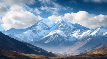 Majestic snow-capped mountains under a blue sky with clouds.