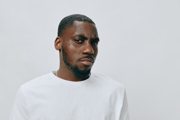 Obraz premium African male model with serious expression wearing a white t shirt against a neutral background, showcasing modern fashion style and confidence
