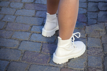 
legs of a person walking down the street in white ankle boots