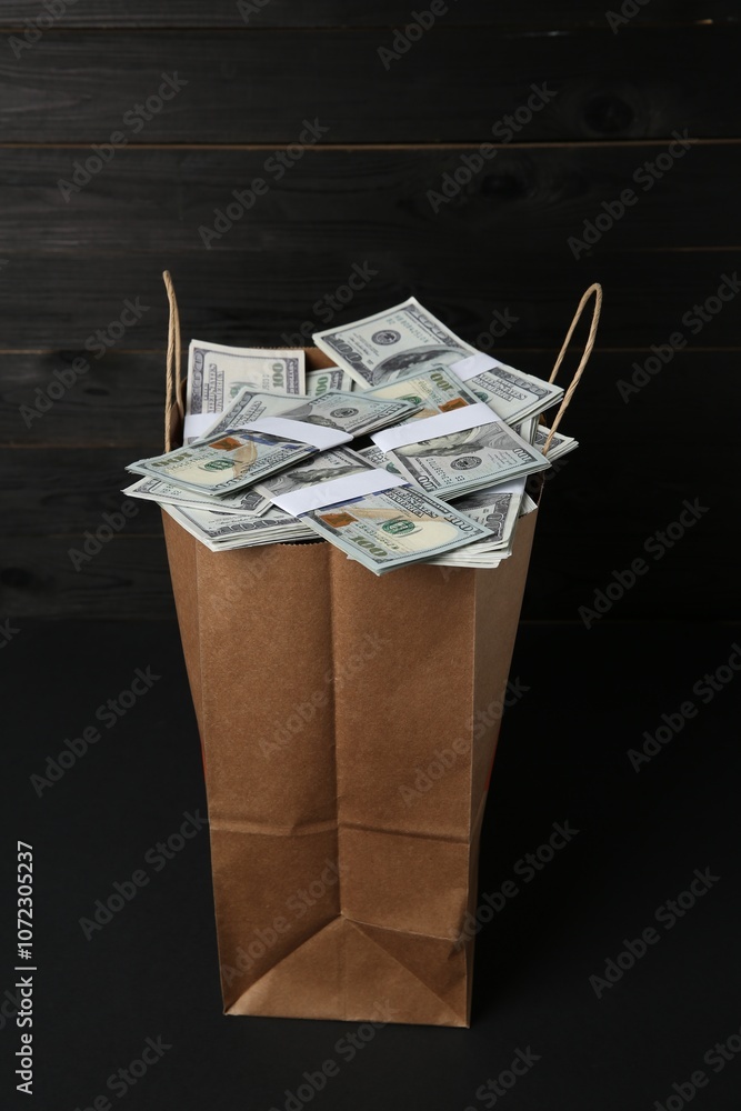 Poster Dollar banknotes in paper bag on black table