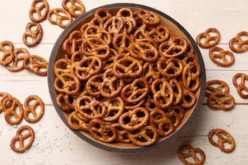 Tasty pretzel crackers with salt on light wooden table, top view