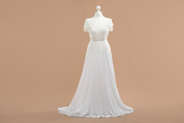 Mannequin with beautiful wedding dress on pale brown background