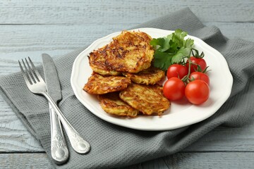 Delicious potato pancakes with tomatoes and parsley served on gray wooden table, closeup