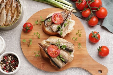 Delicious sandwiches with sprats served in grey table, top view