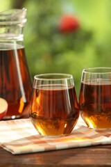 Tasty freshly made apple juice in glasses on wooden table outdoors