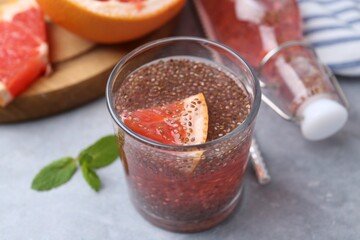 Glass of drink with chia seeds and grapefruit on grey table, closeup