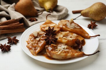 Delicious pears with caramel sauce, almond flakes and anise stars on white table, closeup