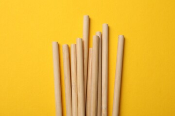 Bamboo drinking straws on yellow background, top view