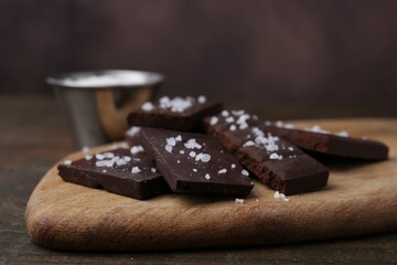 Pieces of chocolate with salt on wooden table, closeup