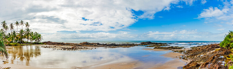 Deserted beach hidden between rocks and coconut trees in the town of Serra Grande on the coast of Bahia, northeastern Brazil