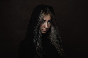 Emotional portrait of a girl with a covered head on a dark background