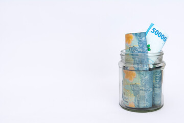 some bills rupiah in a clear jar