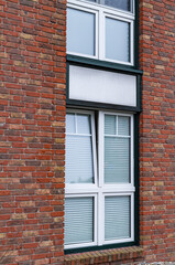 Modern white window with venetian blinds on red brick wall