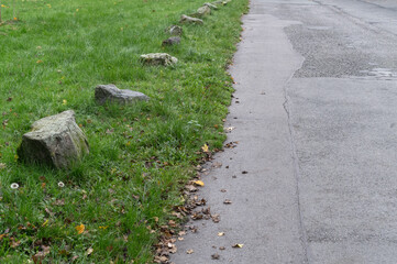 Row of stones separating grass from asphalt road in a park