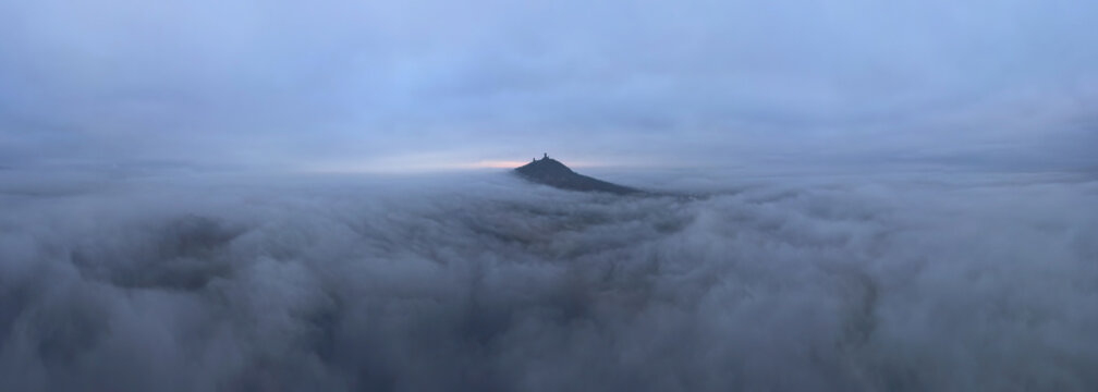 Breathtaking drone air view of Hazmburk (Hasenburg) old medieval castle on solitary hill in Central Bohemian Uplands (Ceske stredohori), Czech Republic, Europe. Foggy cloudy morning skyline panorama.