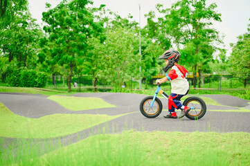 4 years old boy in safety helmeriding balance bike at summer park green trees enjoy happy childhood. .Kids on bicycle in sunny park. Sport for kids.