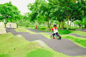 4 years old boy in safety helmeriding balance bike at summer park green trees enjoy happy childhood. .Kids on bicycle in sunny park. Sport for kids.