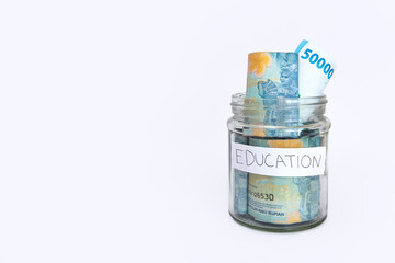 some bills rupiah in a clear jar for education